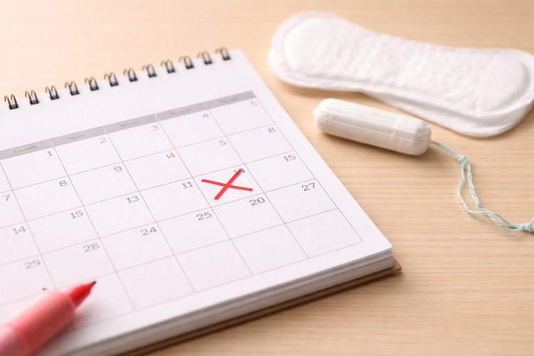 Calendar marked with an X alongside menstrual pad and tampon to show cycle timing.
